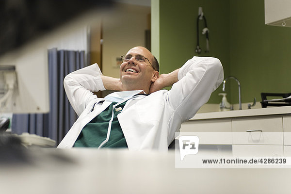 Doctor leaning back in chair with hands behind head  smiling