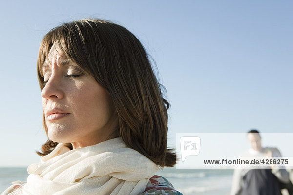 Frau am Strand stehend mit geschlossenen Augen