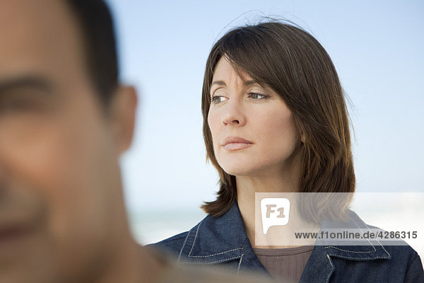 Frau schaut weg mit zerfurchter Stirn  Mann im Vordergrund