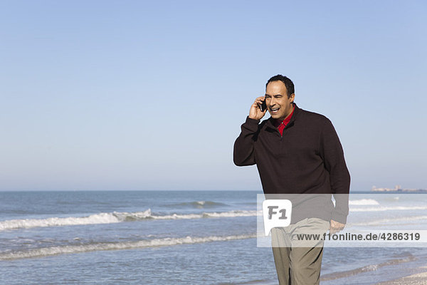 Man talking on cell phone while walking on beach