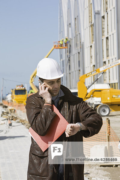 Bauunternehmer mit Handy  Zeitkontrolle