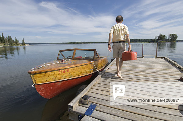 Mann zu Fuß mit Gas kann in Richtung Mahagoni Motorboot  Gunn Lake  Ontario