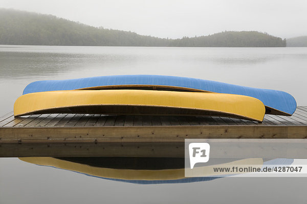 Blue and yellow canoes on cottage dock on a misty morning  Algonquin Park  Ontario