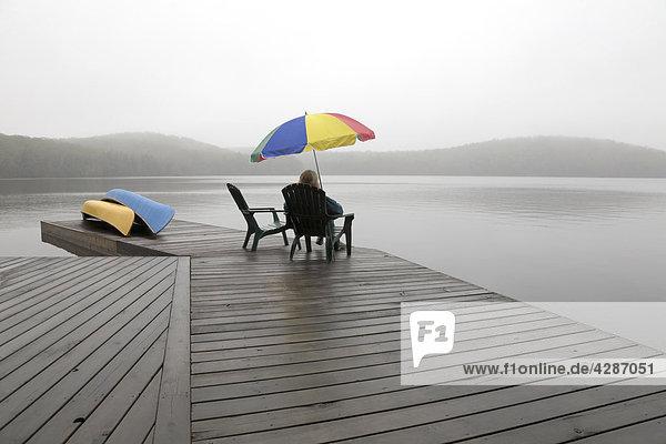 Senior woman on a cottage dock on a misty morning  Algonquin Park  Ontario
