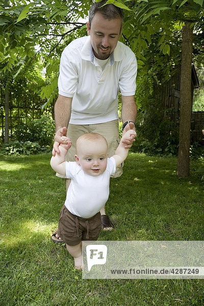 Baby boy learning to walk with the help of his Dad  Ontario