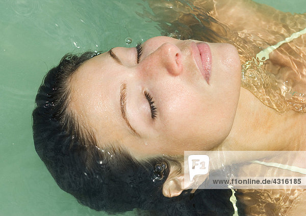 Frau mit geschlossenen Augen  zurücklehnend ins Wasser  Nahaufnahme des Kopfes