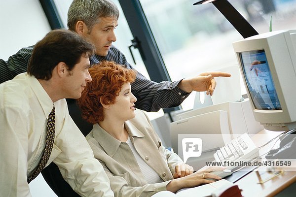 Geschäftskollegen  die gemeinsam am Desktop-Computer arbeiten