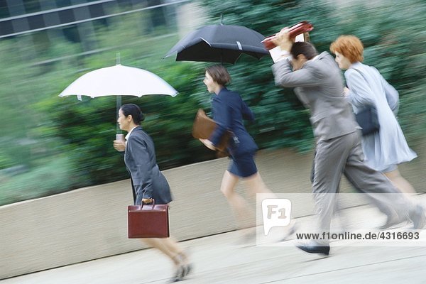 Group of business executives hurrying through rain