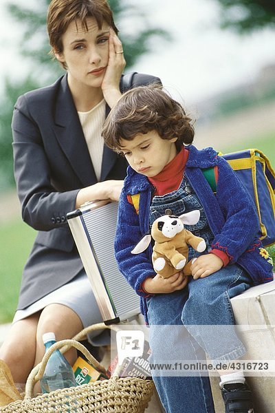 Businesswoman sitting with son  holding head