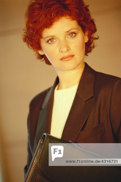Geschäftsfrau stehend mit Aktentasche unterm Arm  Portrait