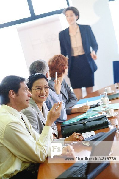 Group of businesspeople sitting around conference table during presentation