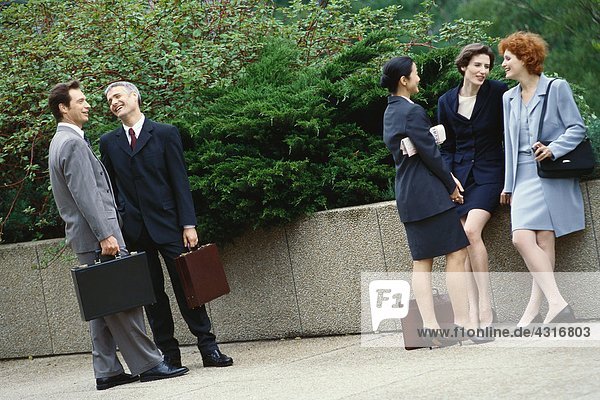 Business executives standing outdoors in groups  chatting