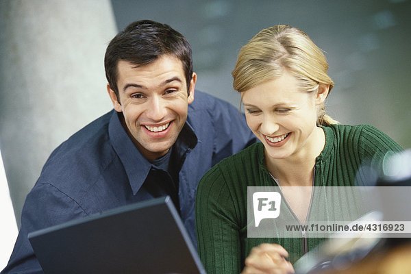 Junge Frau und Mann mit Laptop  lächelnd