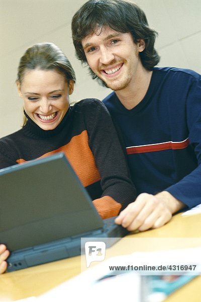 Couple using laptop  smiling