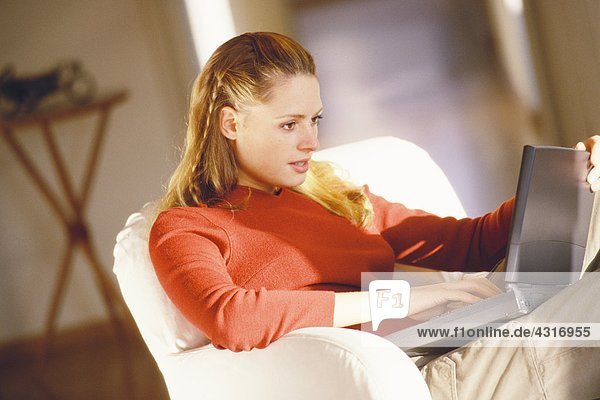 Frau im Sessel sitzend mit Laptop