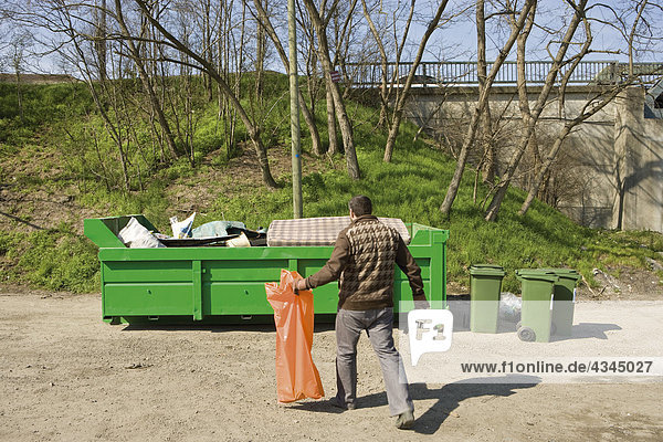 Man taking garbage to dumpster