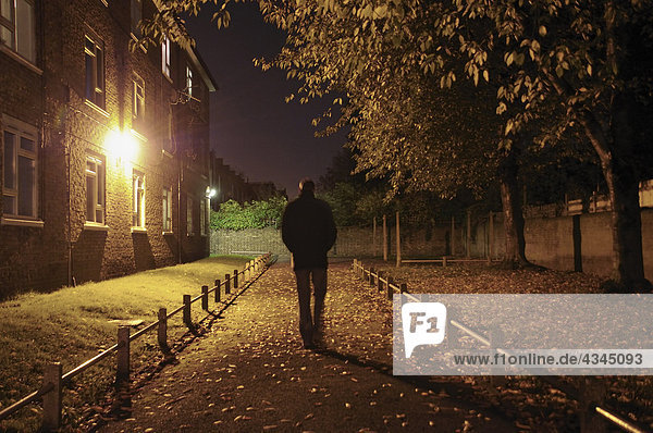 Männlicher Spaziergang entlang der Gasse bei Nacht