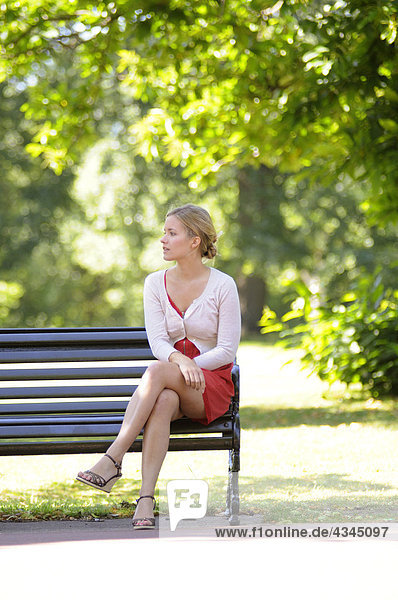 Junge Frau auf Parkbank sitzend