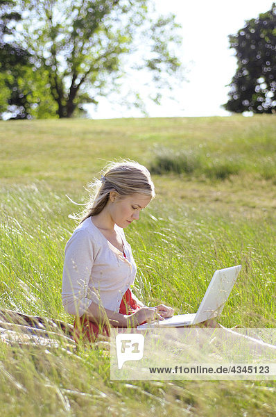 Junge Frau mit Laptop im Park
