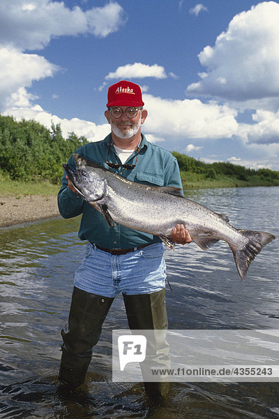Fisherman holding large king salmon along shoreline Nushagak River Southwest AK Summer