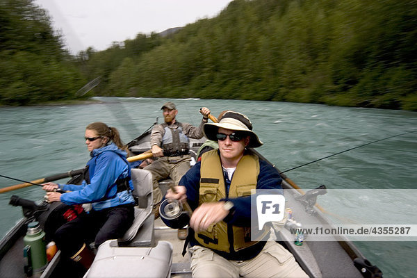 Couple spinfishing from drift boat on Kenai River Kenai Peninsula Alaska Summer Blurred Action