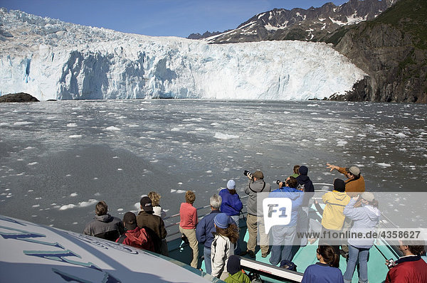 Tourists view glacier from the bow of a Kenai Fjords tour of Resurrection Bay  Seward  Alaska
