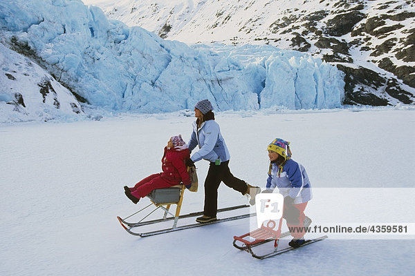 Family kick sledding together on Portage Lake Southcentral Alaska Winter Portage Valley