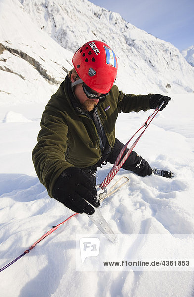 Climber sets a snow picket for protection while on top of Shakes Glacier  Stikine-LeConte Wilderness  Southeast Alaska