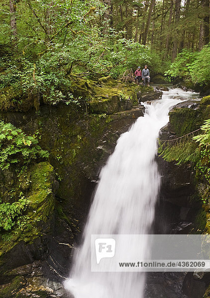 Zwei Wanderer stehen an der Spitze der Sägewerk Creek Falls im Tongass National Regenwald in der Nähe von Juneau  Alaska Southeast