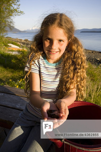Portrait of young Mädchen hält Muscheln aus kammille am Punkt Louisa Strand nördlich von Juneau südöstlichen Alaska Küste Sommer