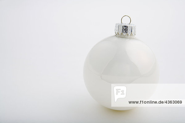 One white Christmas tree bulb ornament with silver hook on white background studio portrait