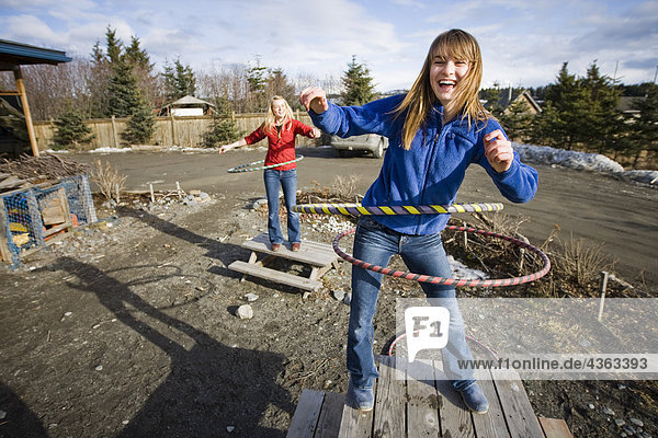Two young women hula-hoop on top of picnic tables in Homer  Alaska