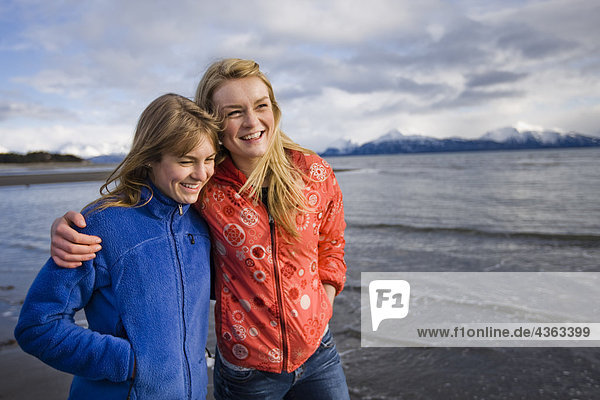 Two young women walk arm in arm at Bishop's Beach in Homer  Alaska