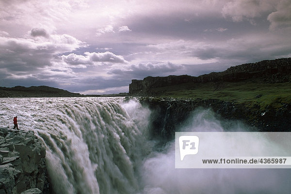 Man stands at edge of Gulfoss waterfalls Iceland