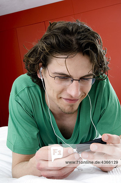 Mann hört MP3-Player  liegt auf dem Bett