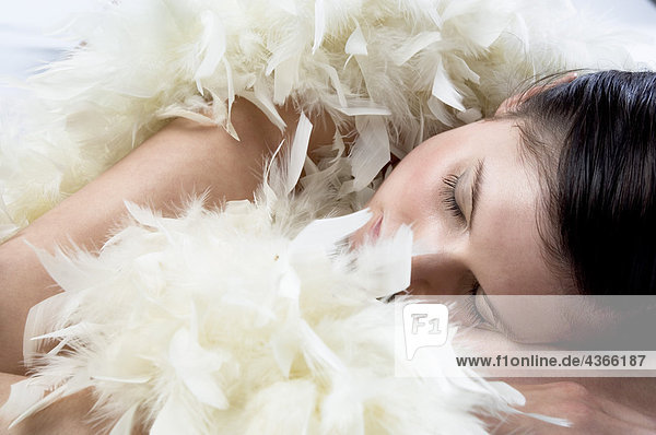 Junge Frau schläft mit weißer Federboa