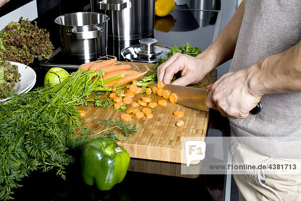 Young man cutting carrots in kitchen