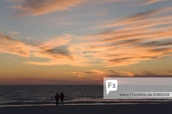 couple  two  people  sea  shore  seashore  watching  clouds  orange  sunset  sky  horizon  end of the day  the end  end  Sarasota  Florida  USA  US  United States  America  horizontal  Sarasota  Florida  USA