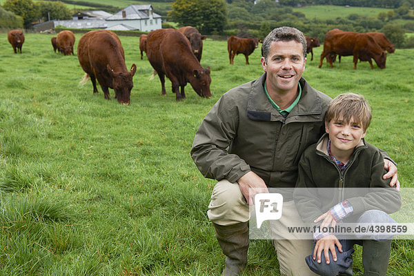 Vater und Sohn auf dem Bauernhof mit Kühen