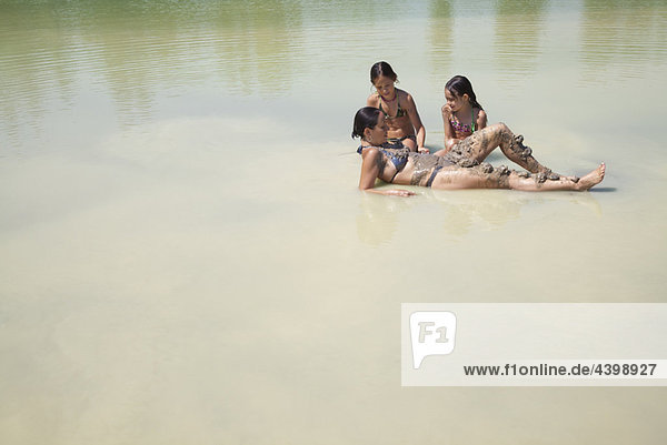 Mutter und Töchter spielen in einem See.
