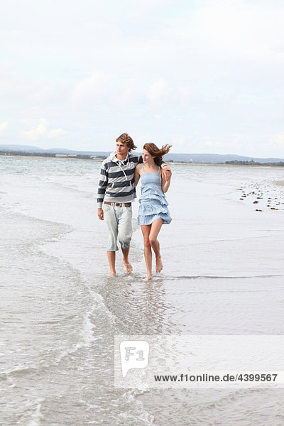 A couple take a romantic beach stroll