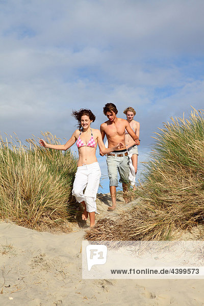 Young friends running over dunes
