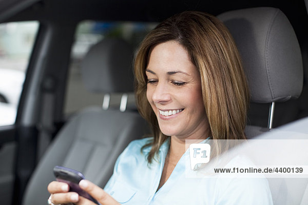 Frau im Auto überprüft Handy