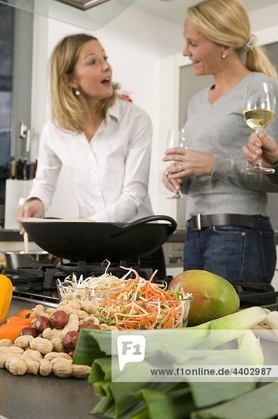 Women with glasses of wine chatting while preparing food