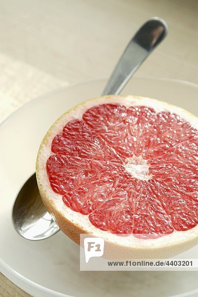Halbe pink Grapefruit mit Löffel