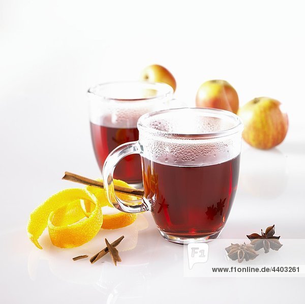 Glühwein in Glas Tassen  Orangenschalen  Gewürzen und Äpfel