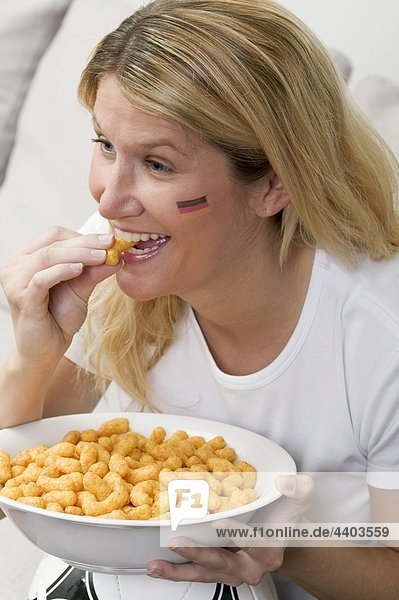 Junge Frau mit deutschen Farben auf ihrem Gesicht essen happe