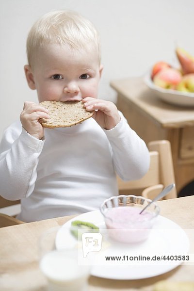 Kleiner Junge beim Frühstück mit Hälfte ein Brot Rollen