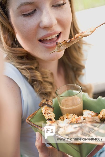 Frau isst gegrillte Satay mit Erdnuss-dip