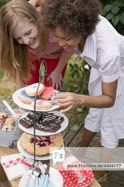 Two women at cake buffet in garden on the 4th of July (USA)